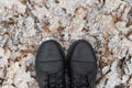 Legs in black boots on snow-covered leaves. Royalty Free Stock Photo