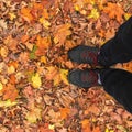 Legs in black sneakers stand on yellow autumn leaves in the park. Autumn concept Royalty Free Stock Photo