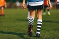 Legs of boy footballer in boots football cleats. Player walking on green grass soccer field at the stadium