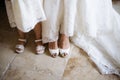 Legs of the bride in white shoes and a little girl in sandals next to her, top view Royalty Free Stock Photo