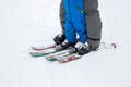 Legs of a child and an adult in warm overalls, skiing. cold day in snowy mountains Royalty Free Stock Photo