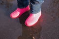 Legs of child in rainboots standing in puddle.Kids in fall. close-up of a baby girls legs with pink rubber boots during