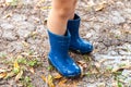 Legs of child wearing pair of blue rubber boots in muddy backyard Royalty Free Stock Photo