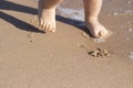 Legs of children stand on the beach. Baby feet in the sand. Summer beach background. Summertime holidays concept. Copy space. Royalty Free Stock Photo