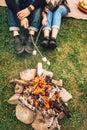 Legs of couple near fire who are roasting marshmallows. Picnic concept. Royalty Free Stock Photo