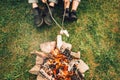 Legs of couple near fire who are roasting marshmallows. Picnic concept Royalty Free Stock Photo