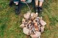 Legs of couple near fire who are roasting marshmallows. Picnic conceptLegs of couple near fire who are roasting marshmallows. Picn Royalty Free Stock Photo