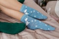 Legs with cute blue socks with white bears and green socks on the bed. Colored socks