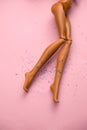 legs of a doll with hair scattered on a soft pink background