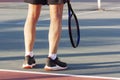 The legs of an elderly man standing with a racket on the court