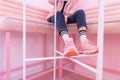 The legs of a fashionable girl in pink sneakers, which sits on a pink sofa. Street fashion. Royalty Free Stock Photo