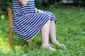 Legs and feet of little girl in dress sitting on a chair on gree Royalty Free Stock Photo
