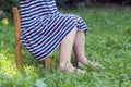 Legs and feet of little girl in dress sitting on a chair on green grass Royalty Free Stock Photo