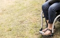 Legs and feet of woman in wheelchair with blue painted toenails and sandals and bluejeans and a black leather purse cropped at edg Royalty Free Stock Photo