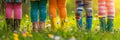 Legs of five children dressed in colorful clothes, on sunny flowering meadow on summer day