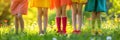 Legs of five children dressed in colorful clothes, on sunny flowering meadow on summer day