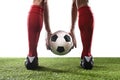 Legs of football player in red socks and black shoes holding the ball in his hands placing free kick