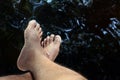 Legs and foots over the water surface stream for relax, travelers are sitting above the water for soaking their legs in the water Royalty Free Stock Photo