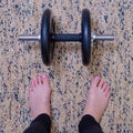 Legs of a girl next to a dumbbell for fitness, closeup