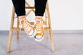 Legs of a girl in orange sneakers and pink socks. The teenager in sneakers and dark jeans sits on a ladder