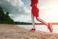 Legs of a girl in a tracksuit closeup, runs along the path of a lake or sea. The concept of a healthy lifestyle, cardio workout.