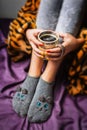 Legs of girl in warm woolen socks and a cup of coffee warming