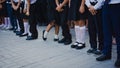 Legs of girls in white golf and boys in suit pants stand in line at the school track on September 1. September 1 - school line.