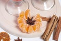 The legs of glass goblets. Nearby peeled mandarin, anise stars and cinnamon sticks