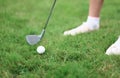 Legs of golfer iron putter and ball on grass