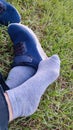 legs in gray socks and sneakers on the green grass in summer, shoes outdoor recreation, relaxation Royalty Free Stock Photo