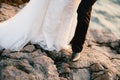 Legs of the groom and bride in a beautiful lace dress, which stand on a rocky beach by the sea Royalty Free Stock Photo