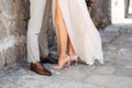 Legs of the groom and the bride embracing near the stone wall on the narrow street of the old gorol, close-up Royalty Free Stock Photo