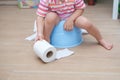 Legs of little Asian 2 years old toddler baby boy child sitting on blue potty holding, playing with toilet paper. Potty training Royalty Free Stock Photo