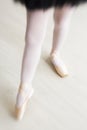 Legs of little balerina wearing pail pink pointe shoes with ribbons Royalty Free Stock Photo