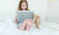 The legs of a little girl in focus, in the focus of a girl with a laptop, a tablet and next to a small kitten Royalty Free Stock Photo