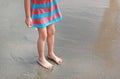 Legs of little kid girl in dress standing on beach Royalty Free Stock Photo