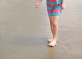 Legs of little kid girl in dress walking on beach Royalty Free Stock Photo