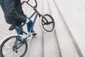 Legs of a man and BMX close-up. The cyclist raises the BMX bike up the stairs. The place for the text