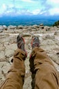 Legs of a man resting in boots for mountain tracking against the backdrop of mountains and valleys with noisy clouds Hiking boots