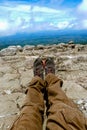 Legs of a man resting in boots for mountain tracking against the backdrop of mountains and valleys with noisy clouds Hiking boots