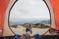 Legs of a man resting in boots for mountain tracking in travel tent against the backdrop of mountains and valleys with