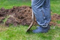 Legs of a man in rubber boots with a shovel near the excavated ground close-up.