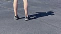 The legs of a man in short shorts and black sneakers. Black and gray asphalt background. Legs of young man in black sneakers.