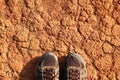 The legs of a man in sneakers a dry polluted red stony soil. Royalty Free Stock Photo