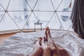 Legs of a man and woman couple in bed against the background of a snow-covered forest in a dome camping