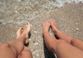 Legs of a man and a woman with her feet in the sea Royalty Free Stock Photo