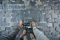 The legs of a man and a woman in leather shoes against the background of stone pavers laid out of stone. Royalty Free Stock Photo