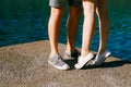 Legs of a man and a woman in sneakers standing hugging each other on the pier close-up, a woman is standing on tiptoe Royalty Free Stock Photo