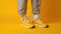 Legs of a man in yellow sneakers on a yellow background. Generative AI. Royalty Free Stock Photo