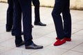 legs of men dressed in suits and black shoes, only one wears red shoes Royalty Free Stock Photo